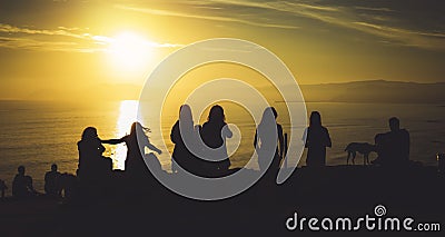 Group of young friends on background beach ocean sunrise, silhouette romantic people dances looking on rear view evening seascape Stock Photo