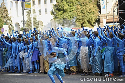 Group of young girls and boys coloured in blue like Avatars standing in the middle of the street and waving hands. Editorial Stock Photo