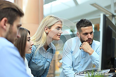 Group of young modern people in smart casual wear having a brainstorm meeting while standing in the creative office. Stock Photo