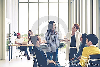 Group of young multiethnic creative team engaged brainstorm in small meeting while standing, sitting and talking together Stock Photo