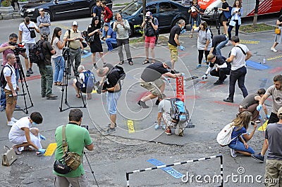 Group of young people activists painting offensive lettering against Putin on asphalt, cameramen shooting. Kyiv, Ukraine Editorial Stock Photo