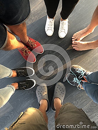 Group of young people feet stand in a circle. Five people in shoes and one barefoot Stock Photo