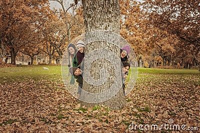 Group of young people hidden behind a tree. Autumn landscape Stock Photo
