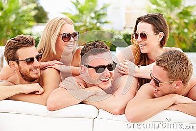 Group Of Young People On Holiday Relaxing By Swimming Pool Stock Photo