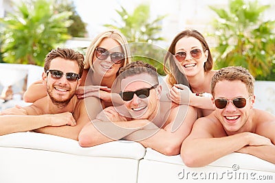 Group Of Young People On Holiday Relaxing By Swimming Pool Stock Photo