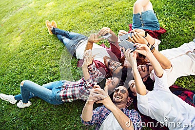 Group of young people laying on the grass in circle, thumbs upGroup of young people laying on the grass in circle, using phones Stock Photo