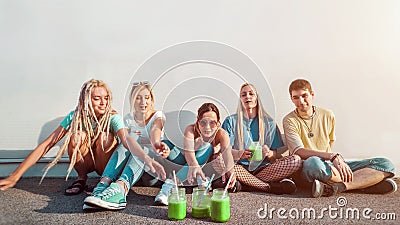 Group of young people reaching for green fruit smoothies, healthy drinks concept, youth and friendship Stock Photo