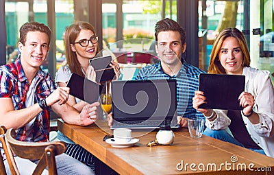 Group of young people sitting at a cafe, holding electronic gadgets Stock Photo