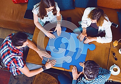 Group of young people sitting at a cafe, holding a puzzle pieces Stock Photo