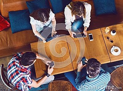 Group of young people sitting at a cafe, with mobiles and tablets Stock Photo