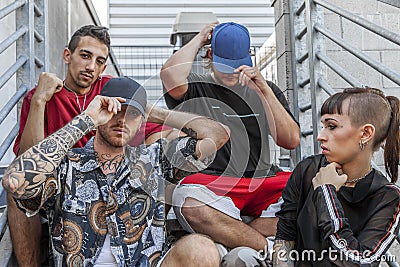 Group of young rappers posing sitting on the metal stairs Stock Photo