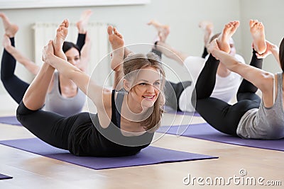 Group of young sporty people practicing yoga lesson, Bow pose Stock Photo