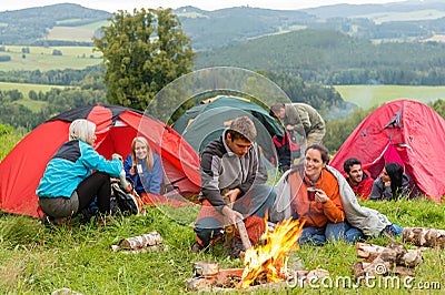 Sitting by campfire friends in tents chatting Stock Photo