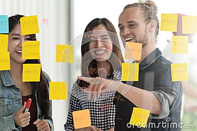 Group of young successful creative multiethnic team smile and brainstorm on project together in modern office with post note or st Stock Photo