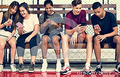 Group of young teenager friends on a basketball court relaxing using smartphone Stock Photo