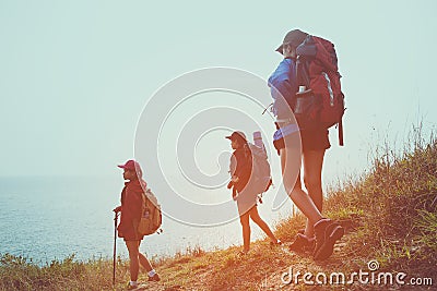Group young women of hikers walking with backpack on a mountain at sunset. Stock Photo