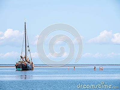 Group of youngsters wading in shallow water and sailboat aground Editorial Stock Photo