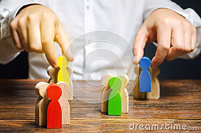 Groups of multicolored wooden people and businessman. The concept of market segmentation. Target audience, customer care. Market Stock Photo