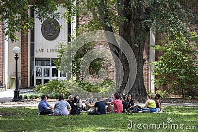 A groups of students sits in a circle on the grass under a tree in front of a law library on a college campus Editorial Stock Photo