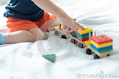 Growing up and kids leisure concept. A child playing with a colored wooden train. Kid builds constructor Stock Photo