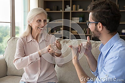 Grownup son communicates with senior mother using gestures Stock Photo