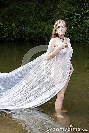 Growth portrait of a girl in a white dress standing in river Stock Photo