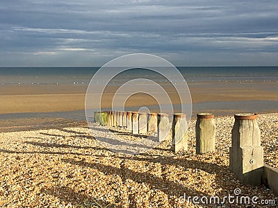 Groynes on Winchelsea Beach to stop the erosion by the tides and weather. Pebble beach with sea and sky landscape - East Sussex UK Stock Photo