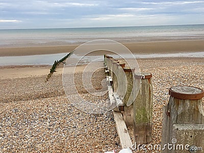 Groynes on Winchelsea Beach to stop the erosion by the tides and weather. Pebble beach with sea and sky landscape - East Sussex UK Stock Photo