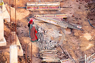 Ladies in saree and men in protective orange vests looking at metal pipes for the plumbing in the foundation of a real Editorial Stock Photo