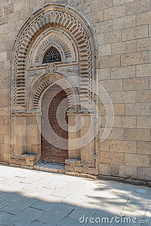 Grunge wooden ornate aged vaulted arched door on exterior decorated stone bricks wall Stock Photo