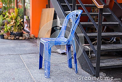 Grungy retro damaged plastic blue chair in the street Stock Photo