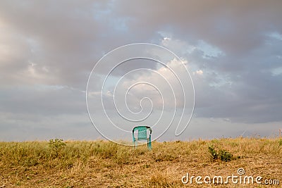 Grungy Retro Damaged Plastic Green Chair Abandoned in a Field Stock Photo