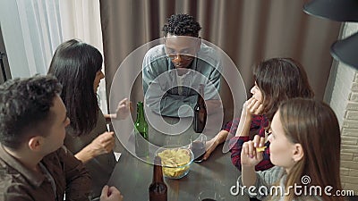 Gruppo multietnico di amici che ridono e bevono birra in un bar o a casa stock footage Gruppo multietnico di amici che ridono e bevono birra in un bar o a casa stock footage