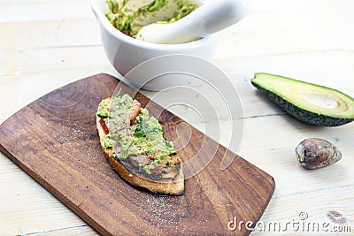 Guacamole on a baguette slice, rustic dÃ©cor with wood boards and a mortar and pestle Stock Photo