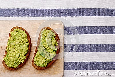 guacamole sandwich on light background. avocado sandwiches on wooden board and textile top view Stock Photo