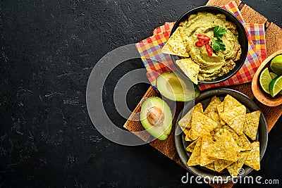 Guacamole. Traditional latinamerican Mexican dip sauce in a black bowl with avocado and ingredients and corn nachos. Avocado Stock Photo