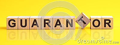 GUARANTOR word is made of wooden building blocks lying on the yellow table, concept Stock Photo