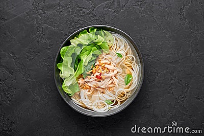 Guay Tiew Gai Cheek or Thai Chicken Noodle Soup in black bowl on dark slate backdrop. Thai food Stock Photo