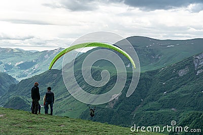 Gudauri, Kazbegi, Georgia: people paragliding through the Devils Valley in the Caucasus mountains. In the background the colorful Editorial Stock Photo