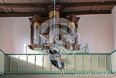 Gudow, Germany, November 13, 2020: Baroque wooden baptism angel hanging on the ceiling in front of the organ in the St. Mary`s Editorial Stock Photo