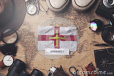 Guernsey Flag Between Traveler`s Accessories on Old Vintage Map. Overhead Shot Stock Photo