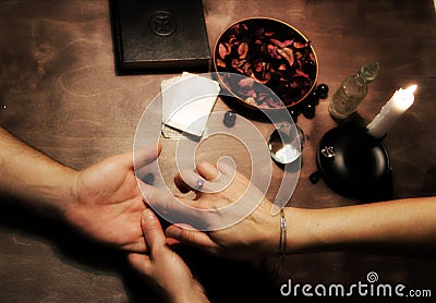 Guessing by hand. Hand guessing. Accessories for divination. Glass crystal, candle on fire, fortune telling book. Stock Photo