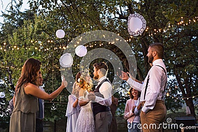 Guests with smartphones taking photo of bride and groom at wedding reception outside. Stock Photo