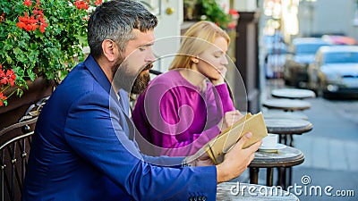 Guide to dating. Meeting people with similar interests. Man and woman sit cafe terrace. Girl interested what he reading Stock Photo