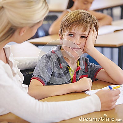 Guiding and inspiring. A young teacher assisting a student with classwork at his desk. Stock Photo