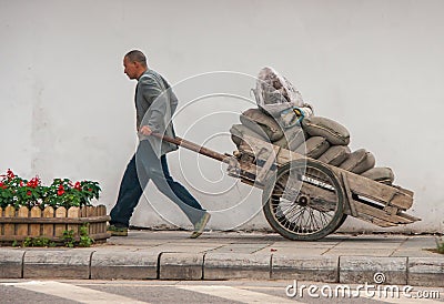 Man pulls cart full of bags, Guilin, China Editorial Stock Photo