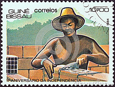 GUINEA-BISSAU - CIRCA 1984: A stamp printed in Guinea-Bissau shows laying bricks, circa 1984. Editorial Stock Photo