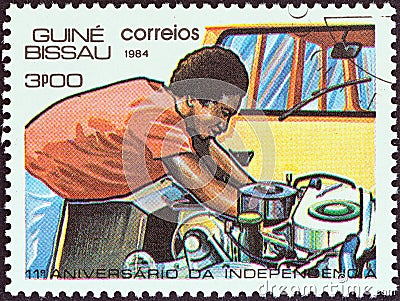 GUINEA-BISSAU - CIRCA 1984: A stamp printed in Guinea-Bissau shows mechanic working on engine, circa 1984. Editorial Stock Photo