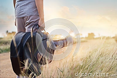 Guitar bag in hand on countryside road in nature background Stock Photo