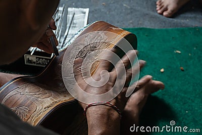 A guitar craftsman are carving a classical guitars made from wood, with Balinese pattern, in a wooden guitar workshop at Guwang Editorial Stock Photo